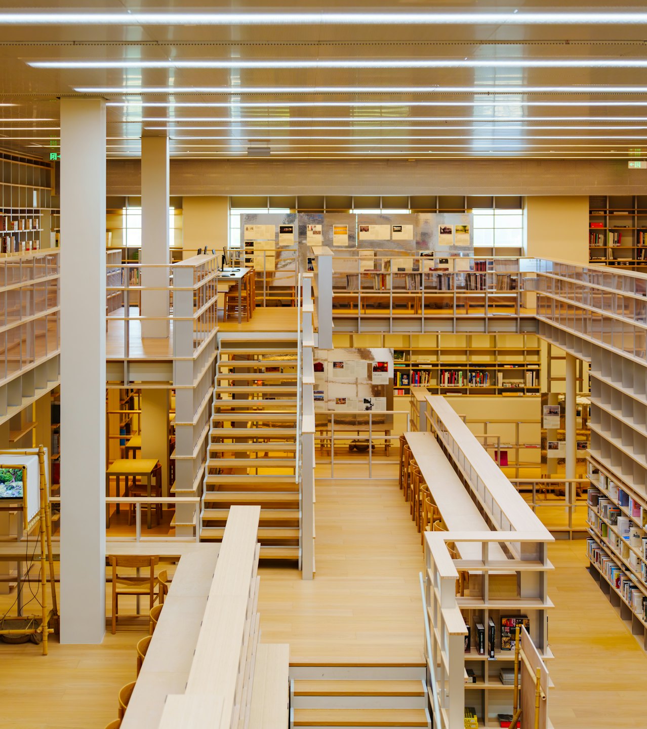 Nowoczesne wnętrze biblioteki z jasnymi drewnianymi podłogami i otwartymi strefami do nauki.
